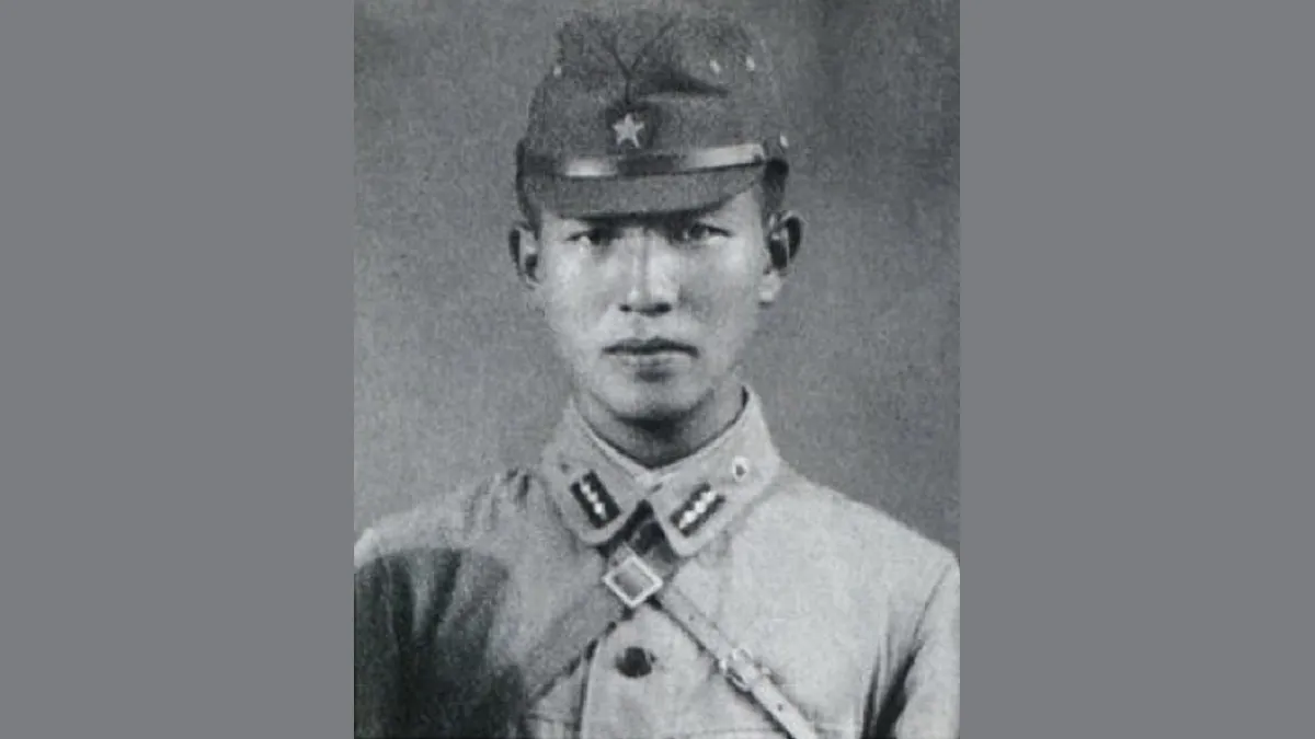 Retrato em preto e branco de um jovem militar japonês de quepe com estrela, uniforme claro e correia de couro atravessada no peito.